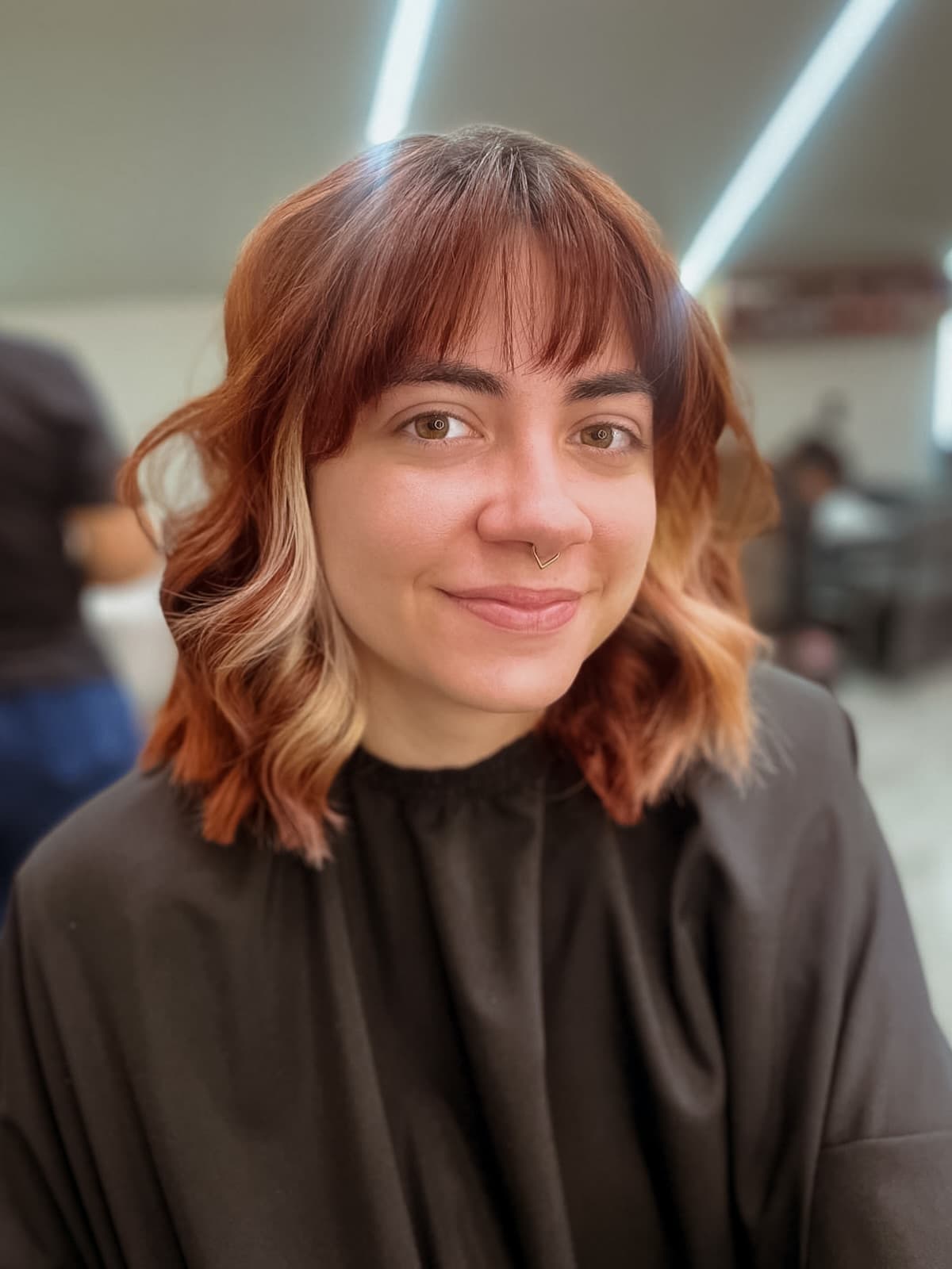 Cliente sorrindo com o corte curto ruivo e mechas claras na frente