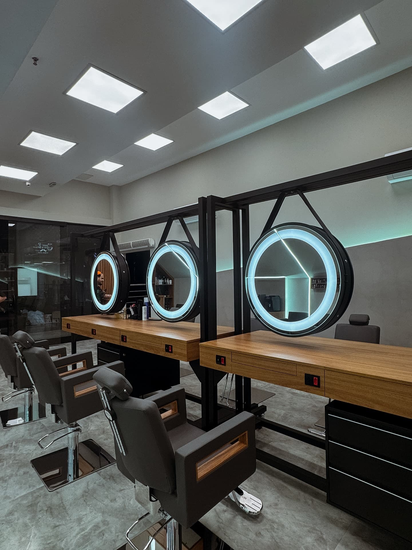 Barbearia com espelhos redondos iluminados e cadeiras de barbeiro