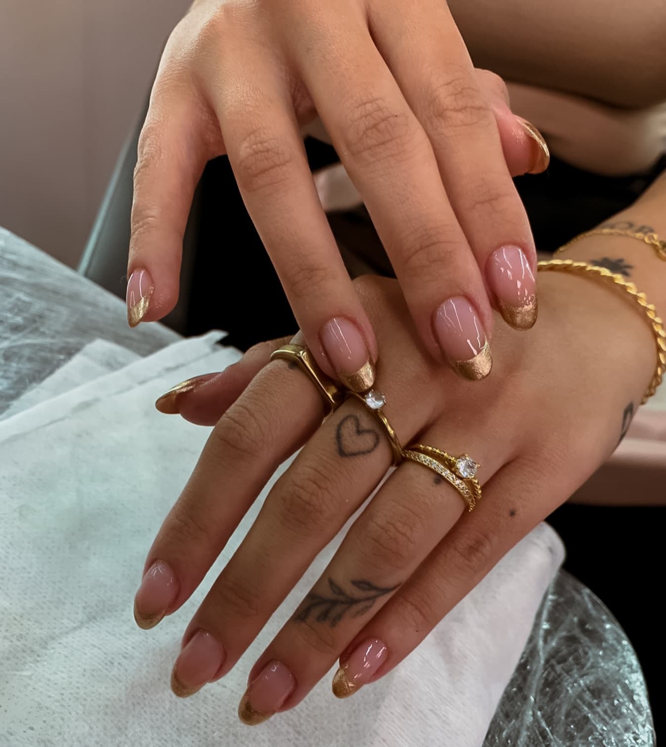 Mãos com unhas longas em francesinha dourada e anéis